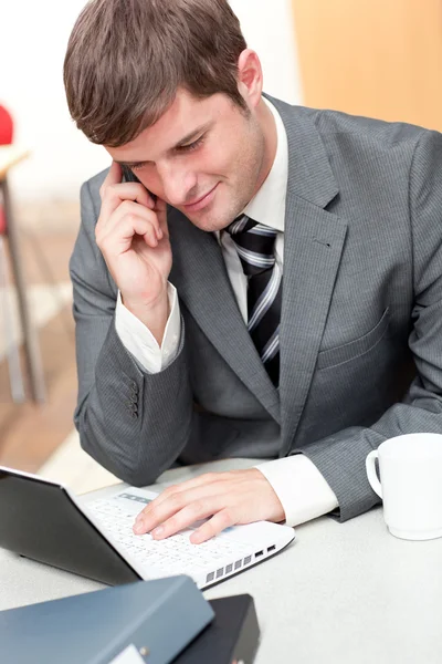 Assertief zakenman praten over telefoon en met behulp van zijn laptop — Stockfoto