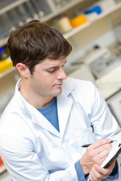 Concentrated scientist writing on a clipboard — Stock Photo, Image