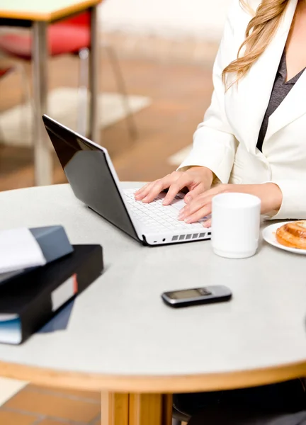 Крупный план занятой деловой женщины, использующей свой ноутбук с мобильным телефоном — стоковое фото