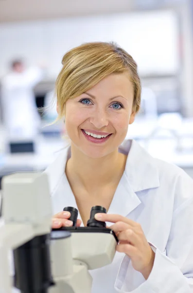 Χαρούμενη θηλυκός επιστήμονας χρησιμοποιώντας ένα μικροσκόπιο — Φωτογραφία Αρχείου
