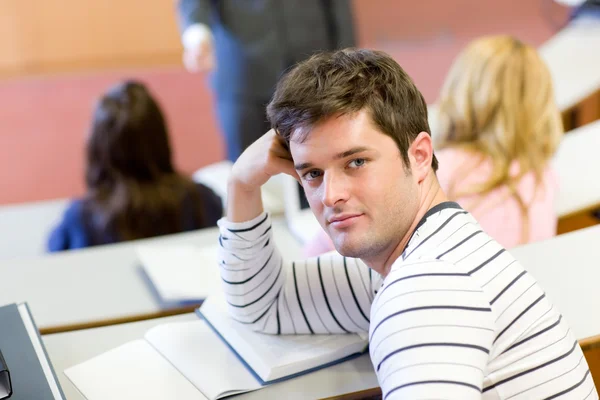 Pohledný muž student úsměv na kameru během univerzitě — Stock fotografie