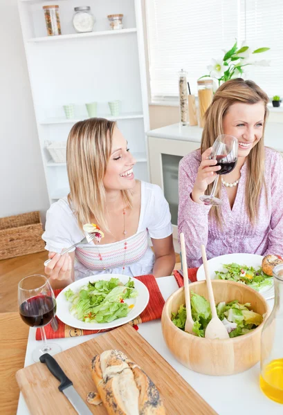 Радісні жінки розважаються під час їжі салат на кухні — стокове фото
