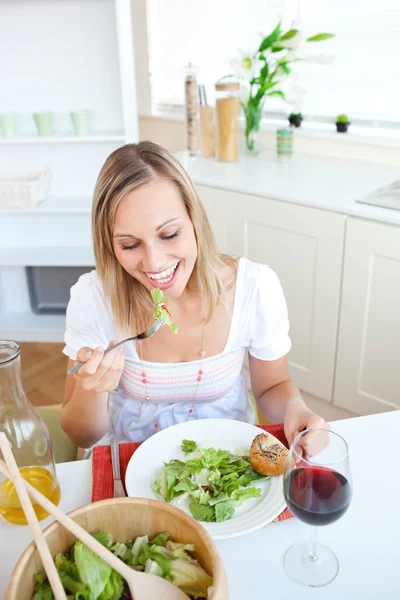 Retrato de una hermosa mujer comiendo una ensalada en la cocina — Foto de Stock