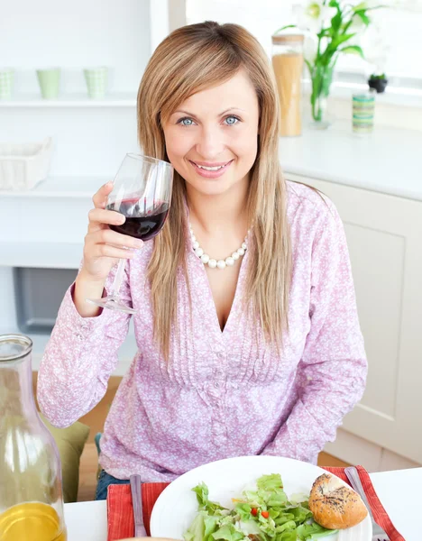 Portrait of a happy woman showing glass of red wine to the camer — Stock Photo, Image