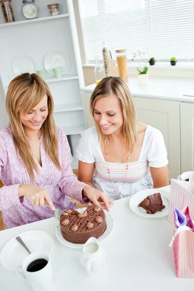 Adorable friend cutting a chocolate cake for a birthday sitting — Stock Photo, Image