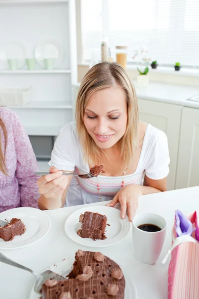 Красивая женщина ест кусок шоколадного торта, сидя в — стоковое фото