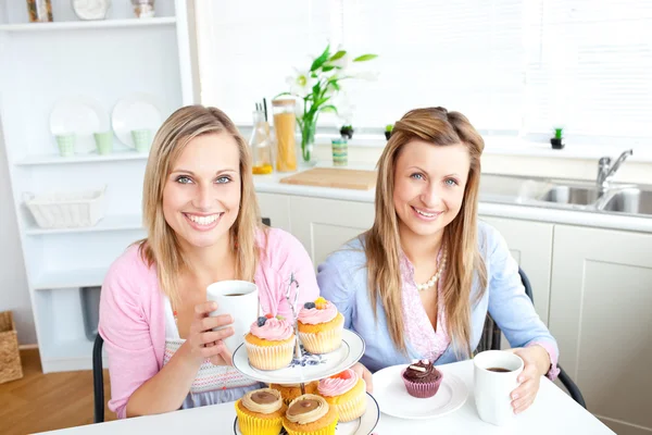Retrato de duas mulheres atraentes com xícaras de café e cupcake — Fotografia de Stock