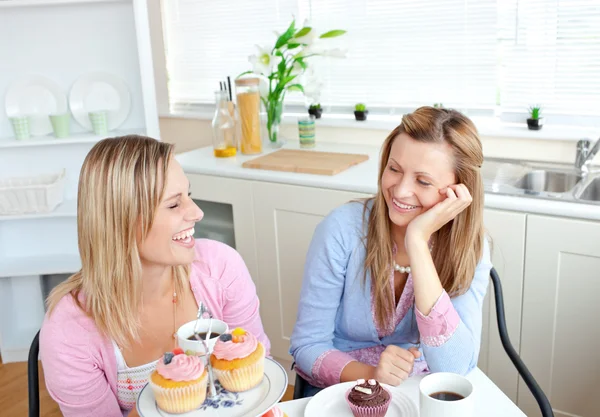 Rindo mulheres comendo cupcakes e beber café sentado em th — Fotografia de Stock