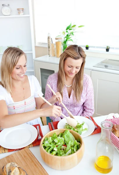 Due donne sane che mangiano insalata in cucina durante l'ora di pranzo a — Foto Stock