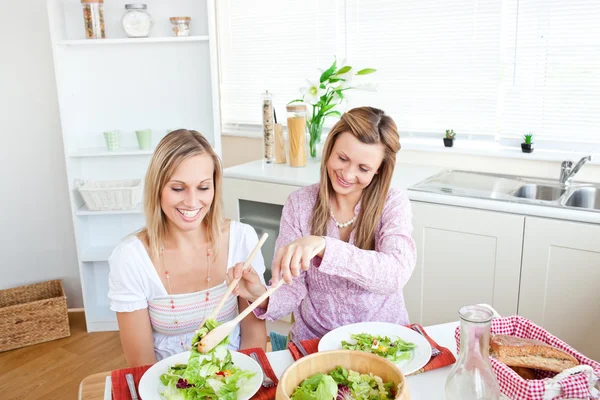 Adorable woman serving salad to her friend sitting at a table — Stock Photo, Image