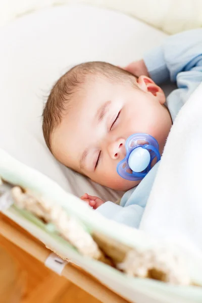 Portrait of a sleeping baby lying in his cradle with his dumm — Stock Photo, Image