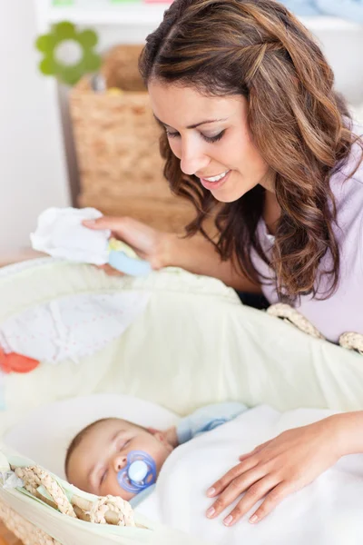 Mère réfléchie berçant son bébé couché dans son berceau — Photo