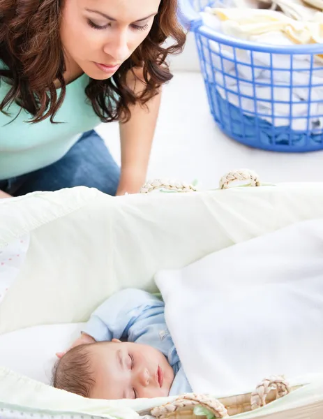 Aufmerksame Mutter, die ihr in der Wiege schlafendes Baby im Auge behält — Stockfoto