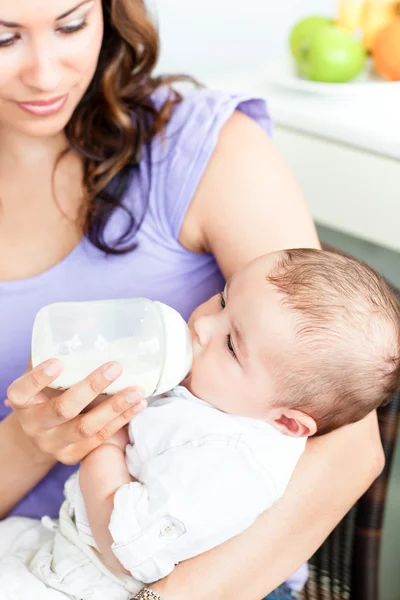 Portrait of a mother feeding her newborn child sitting in the ki — Stock Photo, Image