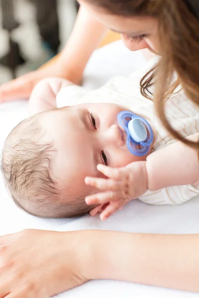 Close-up of a baby lying on a changing table while his mother is — Stock Photo, Image
