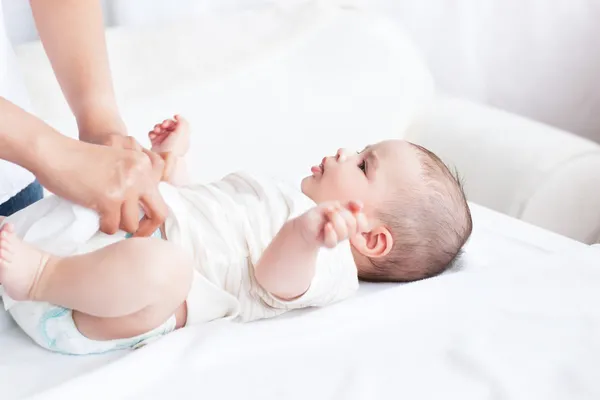 Крупный план молодой матери, меняющей подгузник своего ребенка, лежащей — стоковое фото