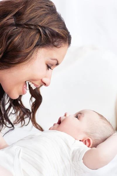Portrait of an adorable mother playing with her baby sitting in — Stock Photo, Image