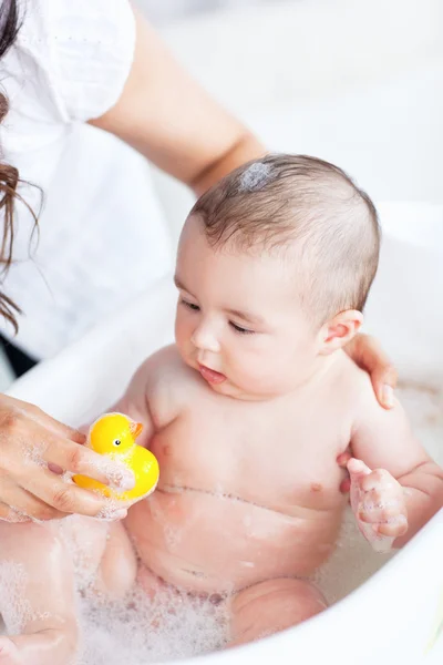 Крупный план ребенка в ванной, играющего с пластиковой уткой — стоковое фото