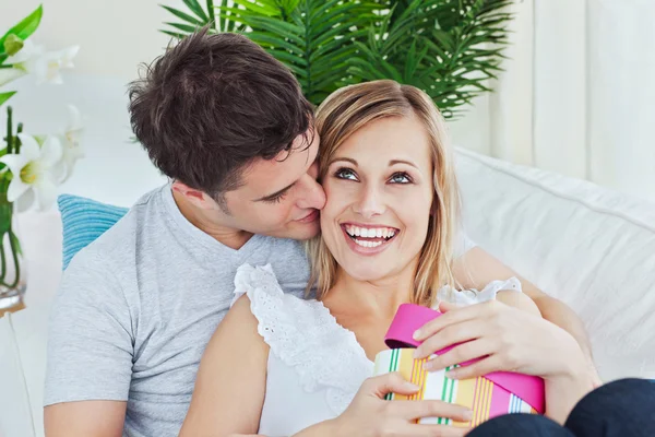 Schöner Mann küsst ihre Freundin, nachdem er ihr ein Geschenk gemacht hat — Stockfoto