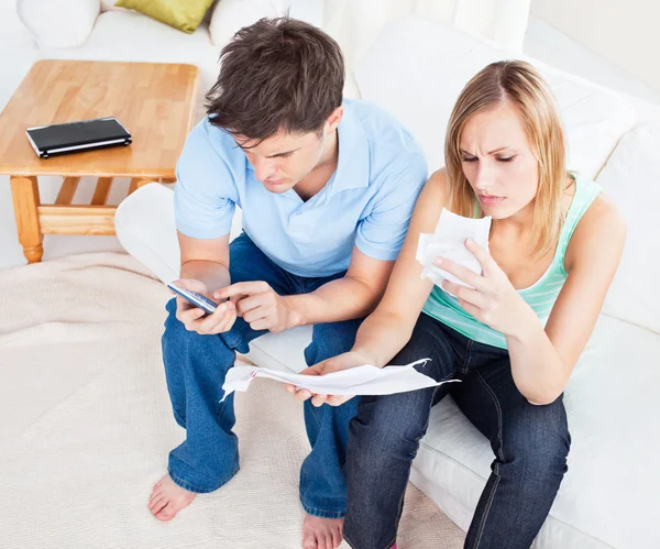 Seriöses Paar berechnet Rechnungen zu Hause auf dem Sofa — Stockfoto