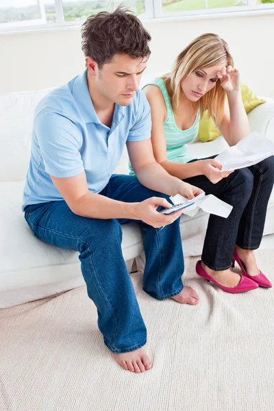 Стрессовая молодая пара рассчитывает счета, сидя в гостиной-ро — стоковое фото