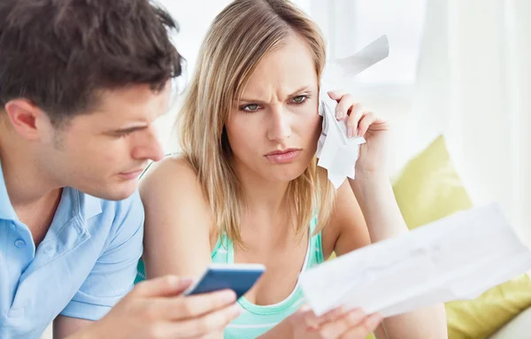 Focused couple calculating bills using a calculator sitting on t — Stock Photo, Image