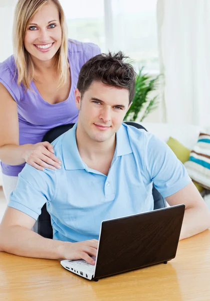 Giovane uomo che utilizza un computer portatile seduto a un tavolo con la sua ragazza — Foto Stock
