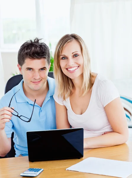 Porträt eines fröhlichen Paares, das mit einem Laptop zusammen sitzt — Stockfoto