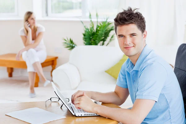Homem feliz usando seu laptop sentado em uma mesa com sua namorada — Fotografia de Stock