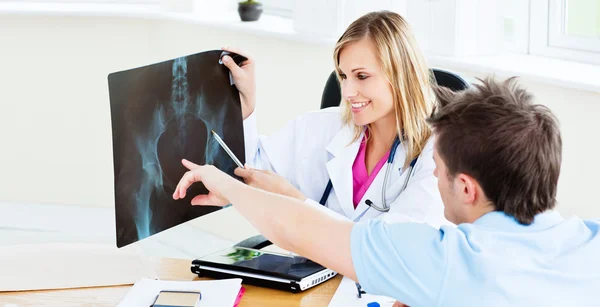 Χαρούμενη γυναίκα γιατρό που δείχνει μια ακτινογραφία σε έναν ασθενή κατά τη διάρκεια μια app — Φωτογραφία Αρχείου