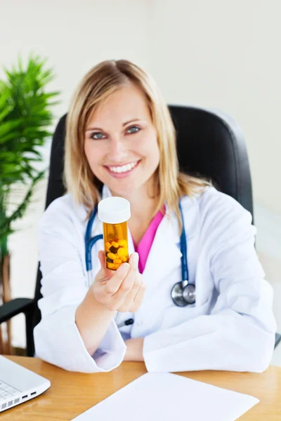 Atraktivní ženský lékař ukazující pilulky s kamerou sedí v — Stock fotografie
