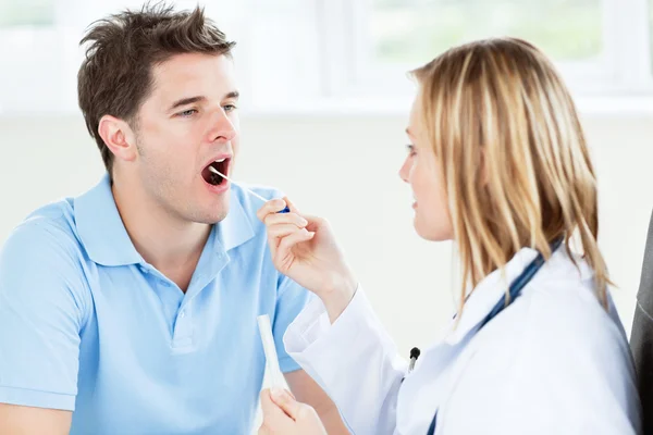 Médico femenino caucásico tomando una muestra de saliva de un paciente masculino —  Fotos de Stock