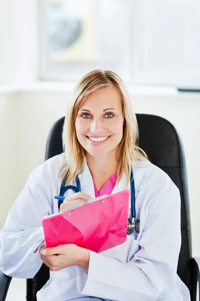 Portrait of a beautiful doctor writing down notes using a clipbo — Stock Photo, Image