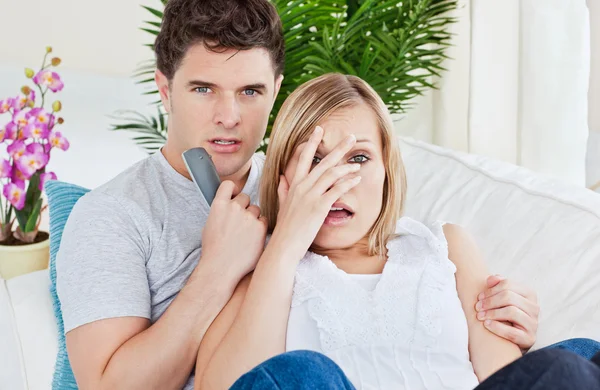 Verängstigtes Paar sieht Horrorfilm zu Hause auf dem Sofa liegend — Stockfoto
