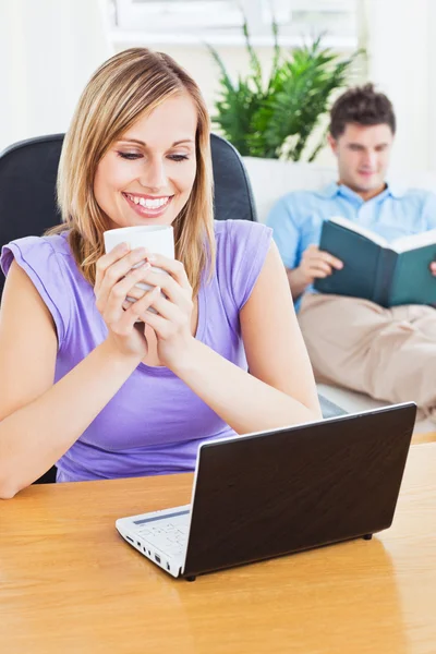 Donna felice con una tazza di caffè utilizzando il computer portatile con il suo ragazzo — Foto Stock