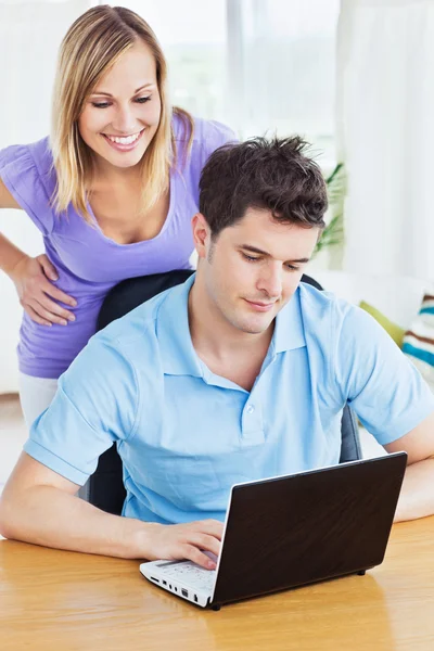 Poważny człowiek za pomocą jego laptop ze swoją dziewczyną, za nim watc — Zdjęcie stockowe