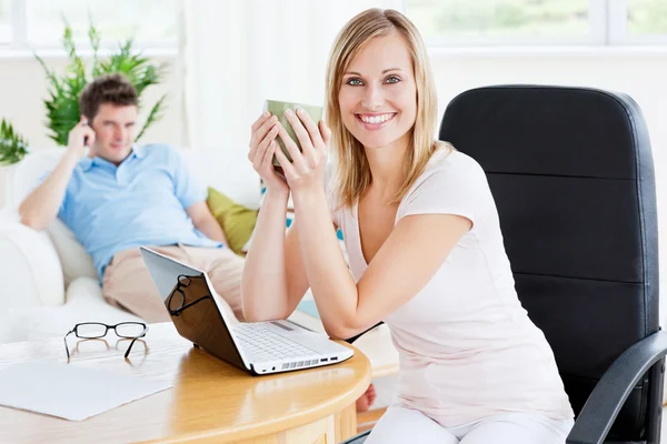 Mulher alegre com uma xícara de café e laptop com seu namorado — Fotografia de Stock