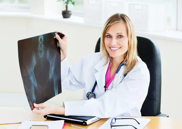 Bella medico femminile mostrando una radiografia per la fotocamera seduta i — Foto Stock