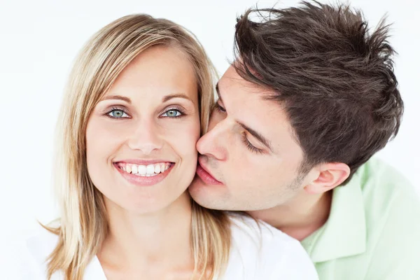 Portrait of a cute man kissing his girlfriend against a white ba — Stock Photo, Image