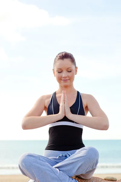 Young caucasian woman doing yoga sitting on the beach during a s — Stock Photo, Image