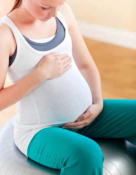 Mladá těhotná žena dotýká její břicho, sedí na fitness bal — Stock fotografie