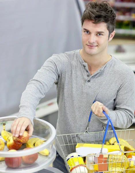 Hombre sano con cesta de la compra de frutas en una tienda de comestibles — Foto de Stock
