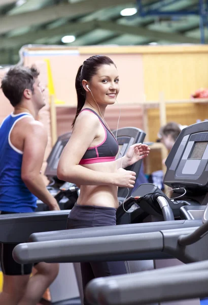 Athletic woman listening to the music while using a treadmill in — Stock Photo, Image