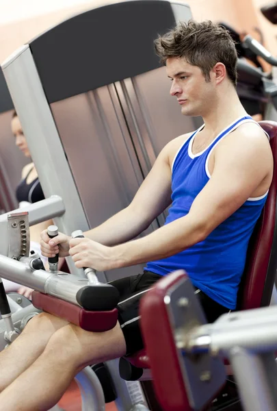 Hombre atlético serio usando una prensa de piernas en la sala de pesas de un — Foto de Stock