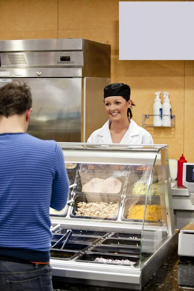 Женщина-повар ждет, когда студент выберет себе обед в кафе — стоковое фото