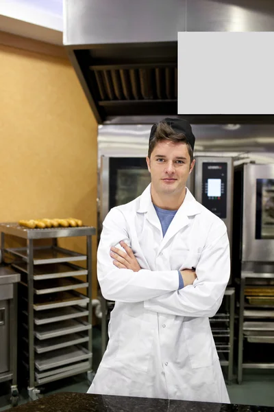 Гордый пекарь, стоящий на кухне и сгибающий руки в ожидании — стоковое фото