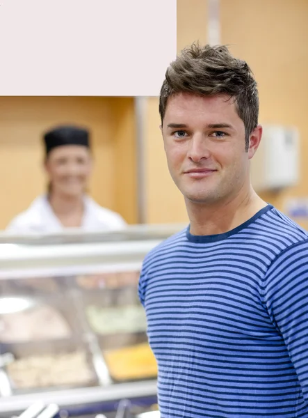 Portrait of a cheerful man choosing his lunch in the cafeteria — Stock Photo, Image