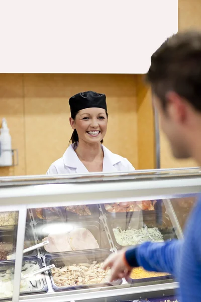 Handsome student showing his choise to the cook in the cafeteria — Stock Photo, Image