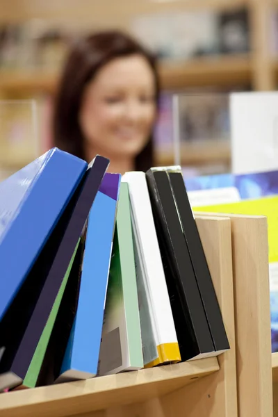 Närbild av en bokhylla i ett bibliotek med kvinnlig kund i th — Stockfoto