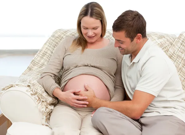 Lindo hombre sintiendo a su bebé poniendo la mano en el vientre de su esposa —  Fotos de Stock